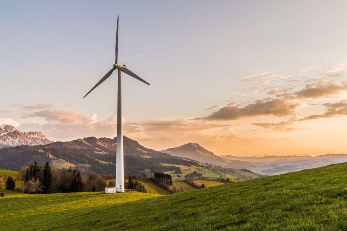 Élevage de Chantime Wind turbine amid rolling hills and mountains at sunset, symbolizing renewable energy and sustainability.