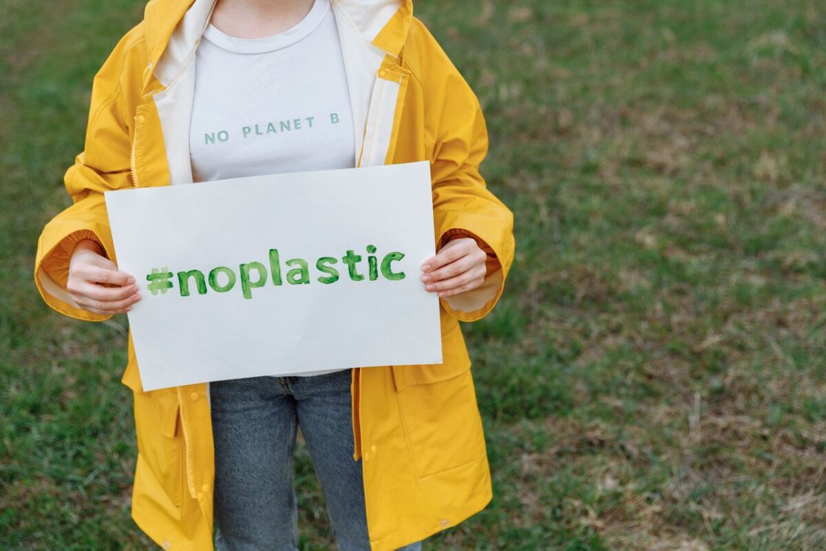 À propos Environmental activist holding #noplastic sign, advocating against plastic use.